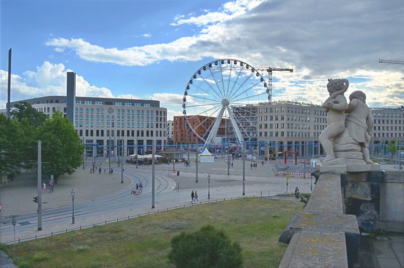 4 - A view from the Dresden Zwinger balcony overlooking Postplatz in Dresden, Germany, featuring the Wheel of Vision Ferris wheel and classical putto stone sculptures in the foreground